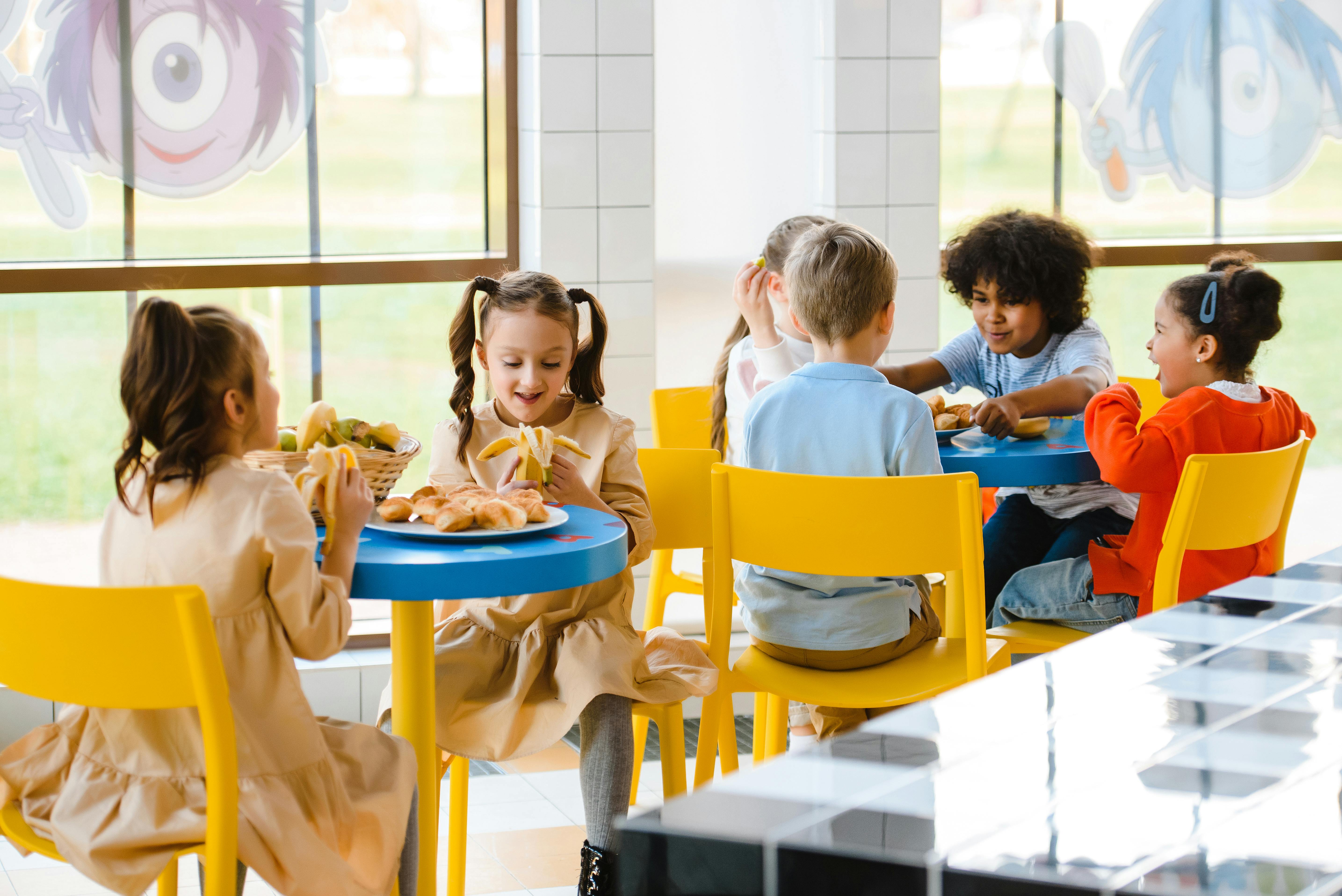 Children eating breakfast together in school hall during free school breakfast clubs trial